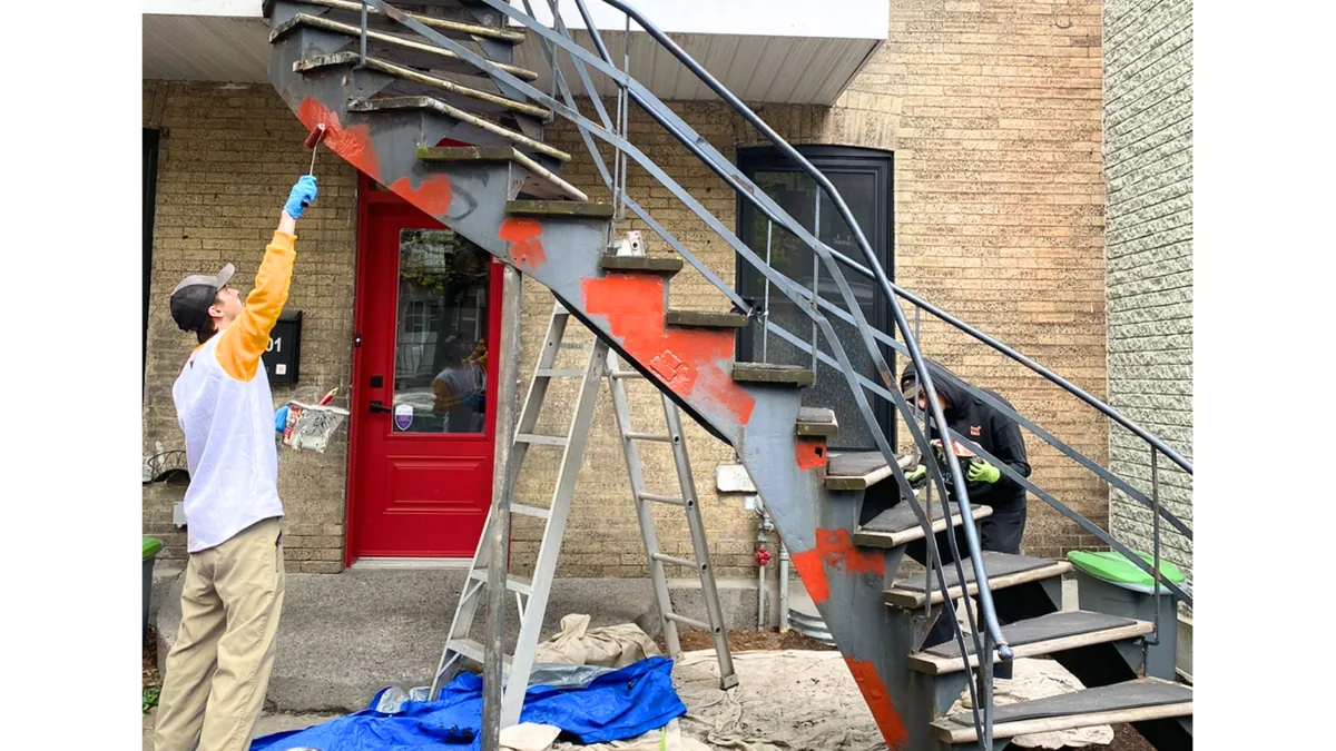 Peintre qui repeint un escalier en colimaçon en fer forgé