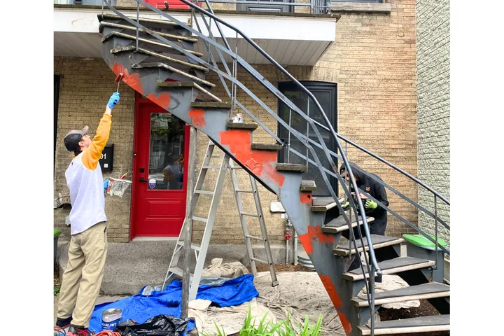 Peintre qui repeint un escalier en colimaçon en fer forgé