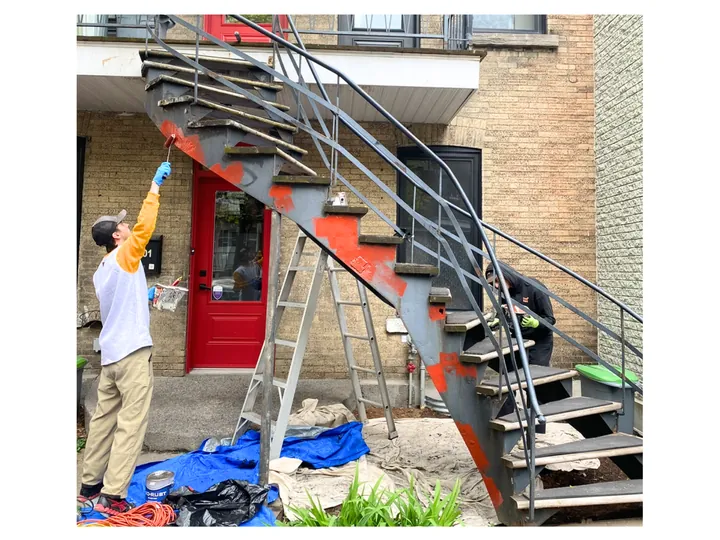 Peintre qui repeint un escalier en colimaçon en fer forgé