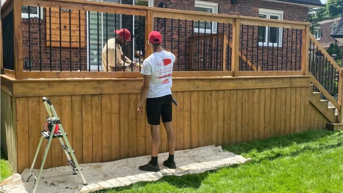 Deux peintres qui teignent le garde-corps d'une terrasse en bois