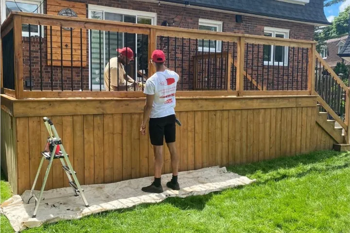 Deux peintres qui teignent le garde-corps d'une terrasse en bois