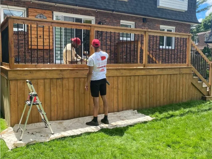 Deux peintres qui teignent le garde-corps d'une terrasse en bois